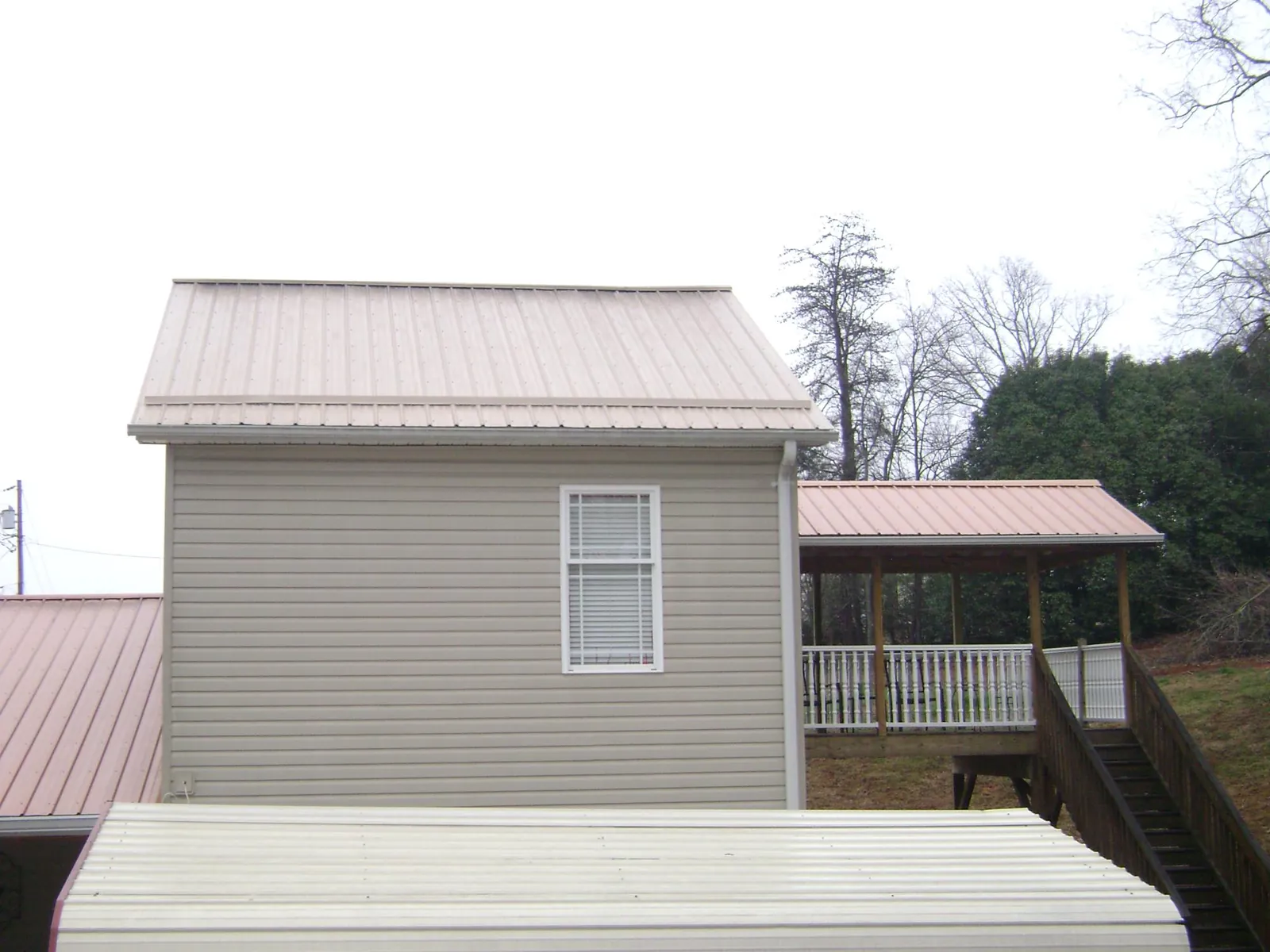 Tan metal roofs on a two story addition and attached porch, from a Roof Replacement job in Northfield